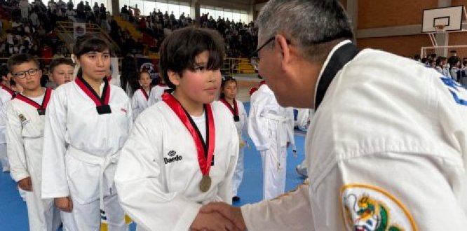 Joven estuduante de taekwondo recibiendo medalla por parte de su entrenador Joven estuduante de taekwondo recibiendo medalla por parte de su entrenador