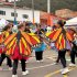 Grupo de niñas y jóvenes participa en una presentación cultural con coloridas alas de mariposa en un espacio comunitario al aire libre.